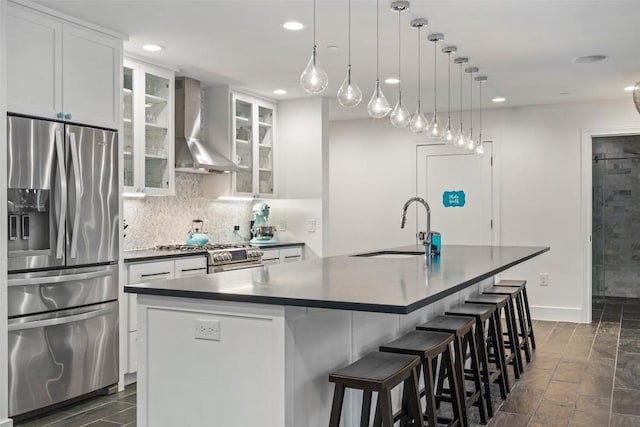 4203 Balcones Dr, Austin, TX 78731 - kitchen with appliances with stainless steel finishes, wall chimney exhaust hood, a sink, dark countertops, and a center island with sink