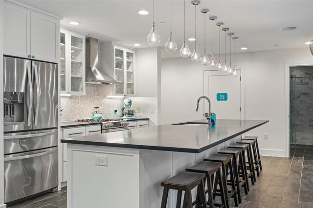 4203 Balcones Dr, Austin, TX 78731 - kitchen featuring stainless steel appliances, wall chimney exhaust hood, dark countertops, a kitchen island with sink, and recessed lighting