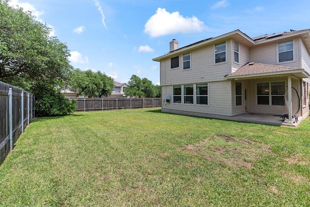 rear view of property featuring a lawn, a patio, a chimney, and a fenced backyard