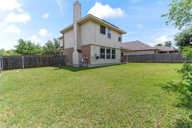 back of house with a fenced backyard, a chimney, and a yard