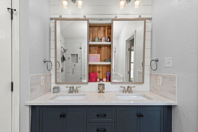 bathroom featuring a sink, a textured wall, and a stall shower