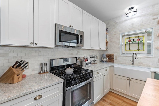kitchen with a sink, white cabinetry, appliances with stainless steel finishes, and tasteful backsplash