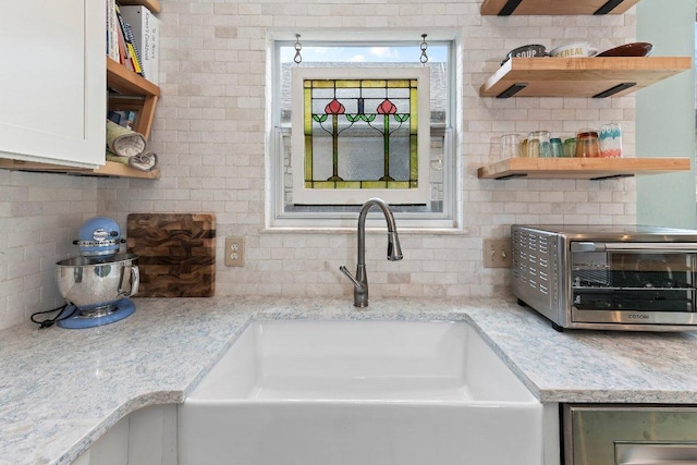 kitchen with open shelves, decorative backsplash, a sink, and a toaster