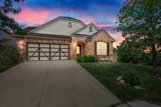 243 Mancos Dr, Georgetown, TX 78626 - view of front of property featuring an attached garage, a yard, stone siding, and concrete driveway