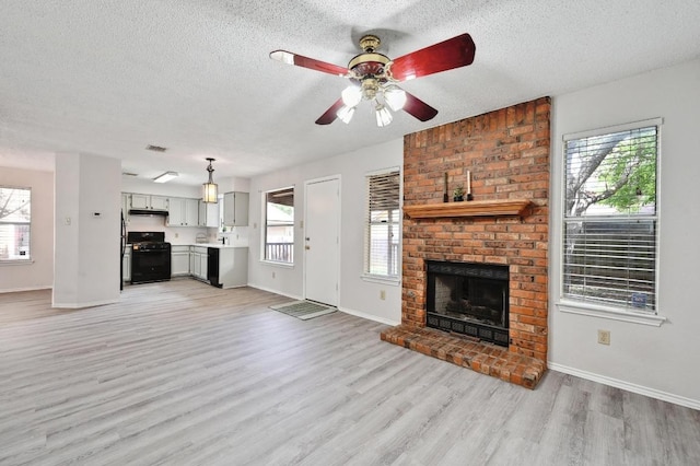 unfurnished living room featuring baseboards, a textured ceiling, light wood finished floors, and a ceiling fan