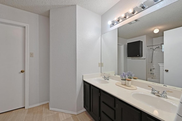full bath with a sink, double vanity, and a textured ceiling