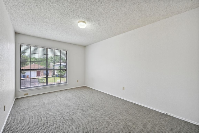 spare room with carpet floors, baseboards, and a textured ceiling