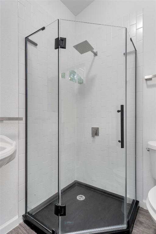bathroom featuring toilet, a shower stall, and wood finished floors