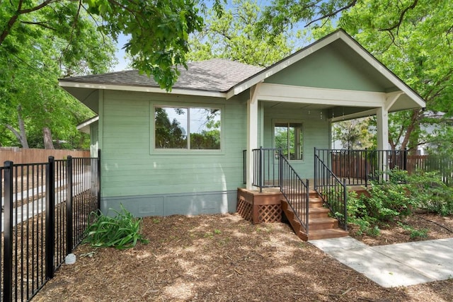 bungalow-style house with covered porch, crawl space, fence, and a shingled roof