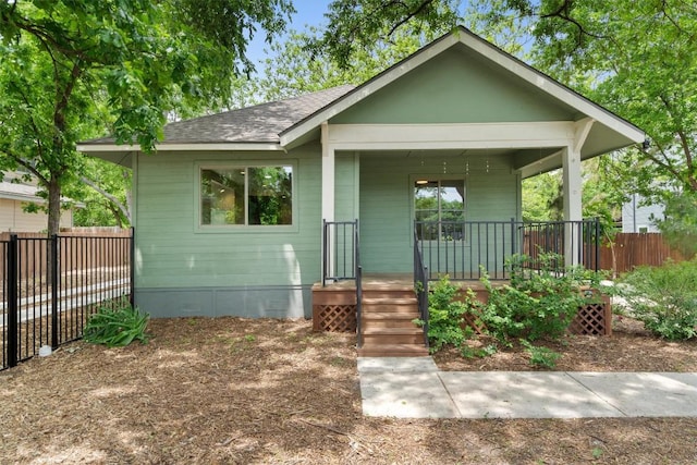 bungalow-style house with a porch, fence, and roof with shingles