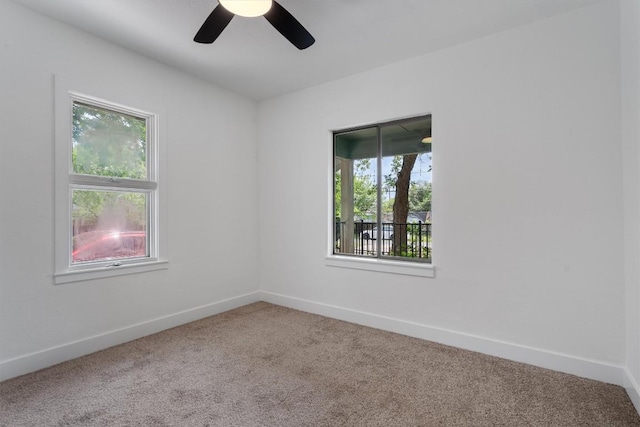 carpeted empty room with a ceiling fan and baseboards