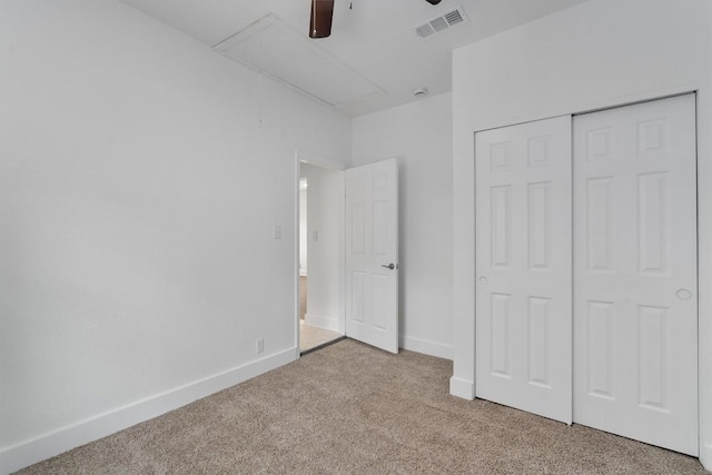 unfurnished bedroom with visible vents, a closet, baseboards, attic access, and carpet flooring