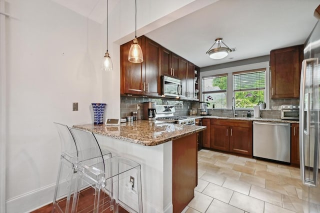 1185 Coleto St, Austin, TX 78702 - kitchen featuring stainless steel appliances, decorative backsplash, a peninsula, and light stone counters