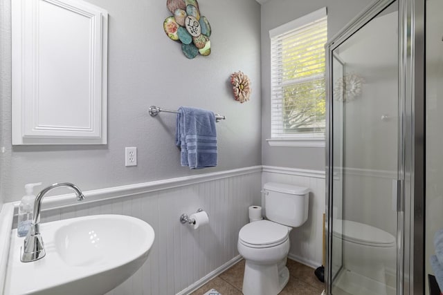 376 Sweet Gum Dr, Kyle, TX 78640 - bathroom featuring toilet, a sink, a stall shower, a wainscoted wall, and tile patterned flooring