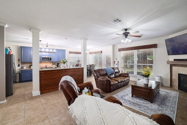 376 Sweet Gum Dr, Kyle, TX 78640 - living area with ornate columns, a ceiling fan, a tile fireplace, and light tile patterned flooring