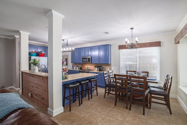 376 Sweet Gum Dr, Kyle, TX 78640 - dining area featuring a chandelier, crown molding, light tile patterned floors, baseboards, and ornate columns