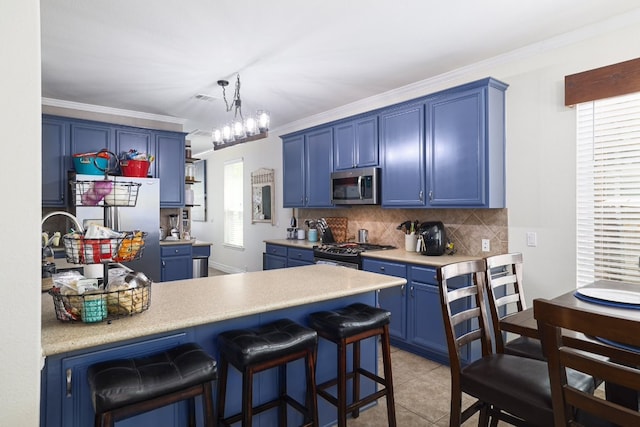 376 Sweet Gum Dr, Kyle, TX 78640 - kitchen with blue cabinets, stainless steel appliances, tasteful backsplash, a kitchen bar, and light countertops
