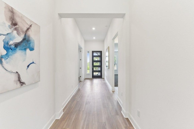 corridor featuring recessed lighting, light wood-style flooring, and baseboards
