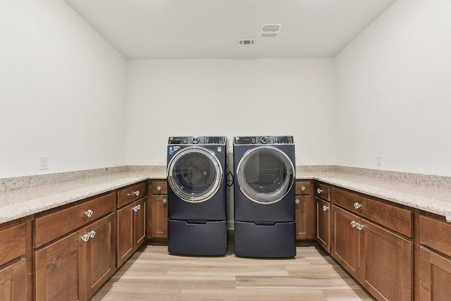 laundry area featuring visible vents, washing machine and dryer, and light wood-type flooring