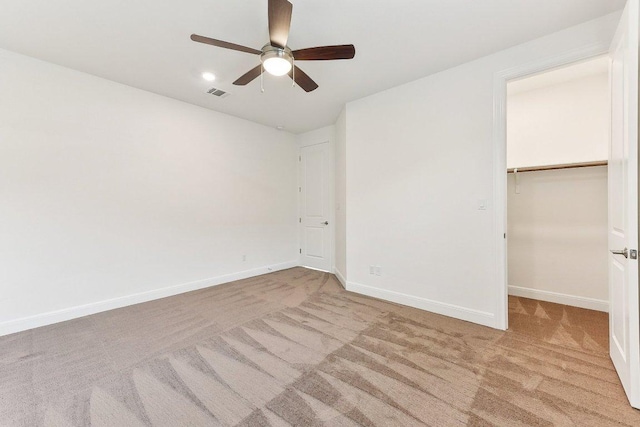 unfurnished bedroom with visible vents, a closet, baseboards, a walk in closet, and carpet flooring