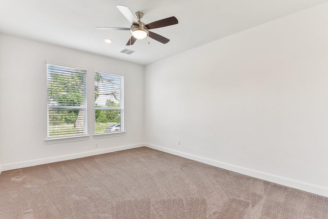 unfurnished room featuring light colored carpet, a ceiling fan, baseboards, and visible vents