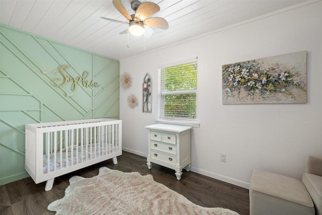 bedroom featuring baseboards, ceiling fan, a crib, and wood finished floors