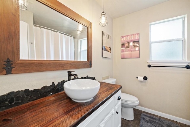 bathroom featuring toilet, baseboards, tile patterned floors, and vanity