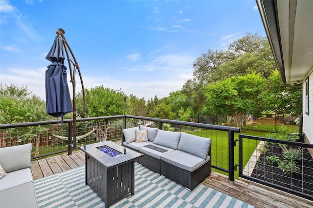 wooden terrace featuring a lawn and an outdoor living space with a fire pit