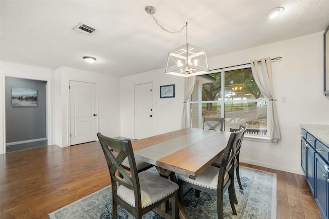 dining space featuring an inviting chandelier, baseboards, wood finished floors, and visible vents