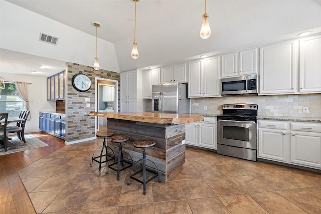 kitchen featuring backsplash, a kitchen bar, visible vents, appliances with stainless steel finishes, and white cabinets