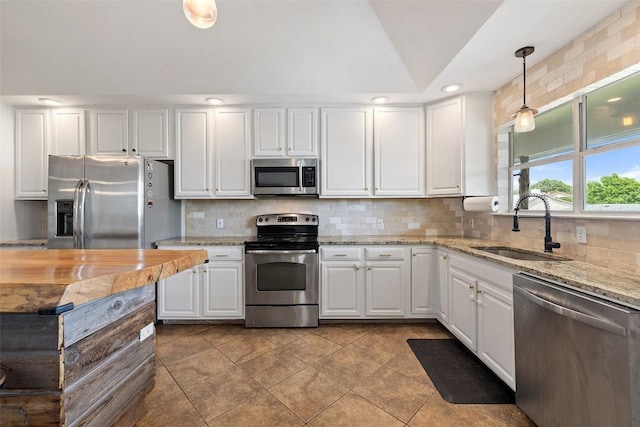 kitchen featuring white cabinets, stainless steel appliances, a sink, and backsplash