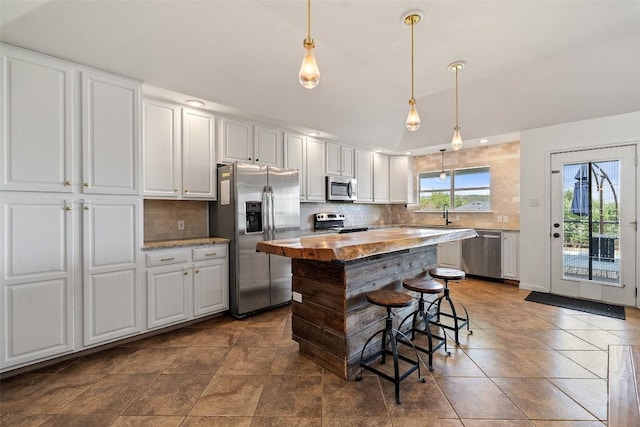 kitchen with white cabinets, stainless steel appliances, vaulted ceiling, and decorative backsplash