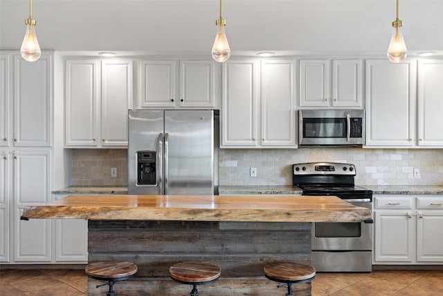 kitchen with white cabinetry, butcher block countertops, appliances with stainless steel finishes, and light tile patterned floors