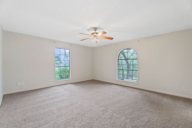 empty room featuring carpet floors, ceiling fan, and a wealth of natural light