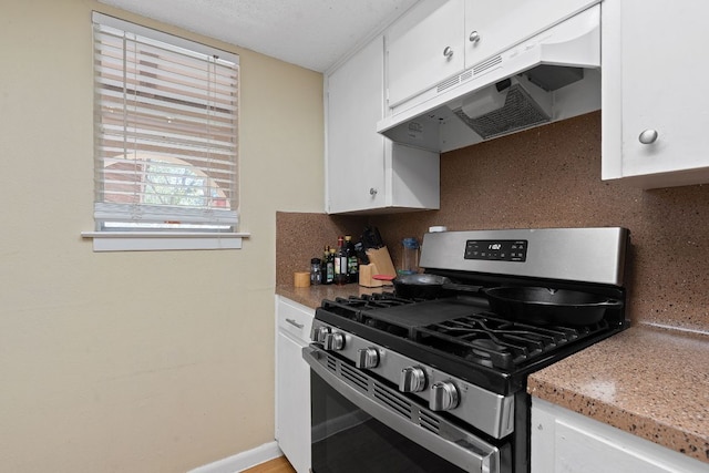kitchen with gas stove, light countertops, white cabinetry, backsplash, and under cabinet range hood