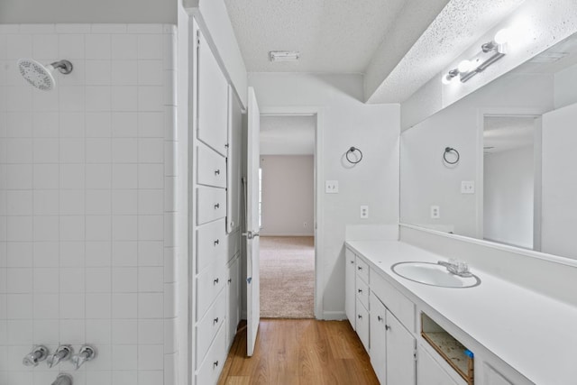 bathroom featuring vanity, a textured ceiling, walk in shower, and wood finished floors