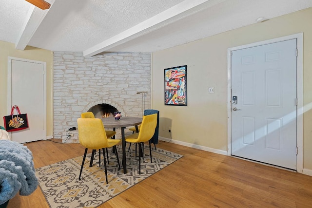 dining room with baseboards, beamed ceiling, a textured ceiling, and wood finished floors