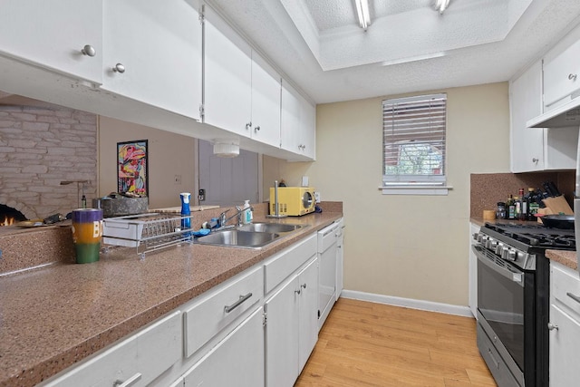 kitchen with white appliances, light wood-style floors, baseboards, white cabinetry, and a sink