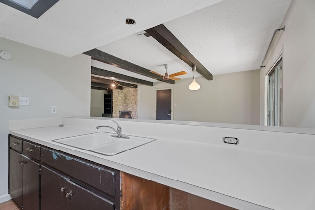 kitchen with a sink, ceiling fan, beam ceiling, and light countertops