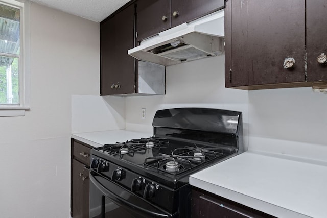 kitchen featuring gas stove, light countertops, under cabinet range hood, and dark brown cabinets
