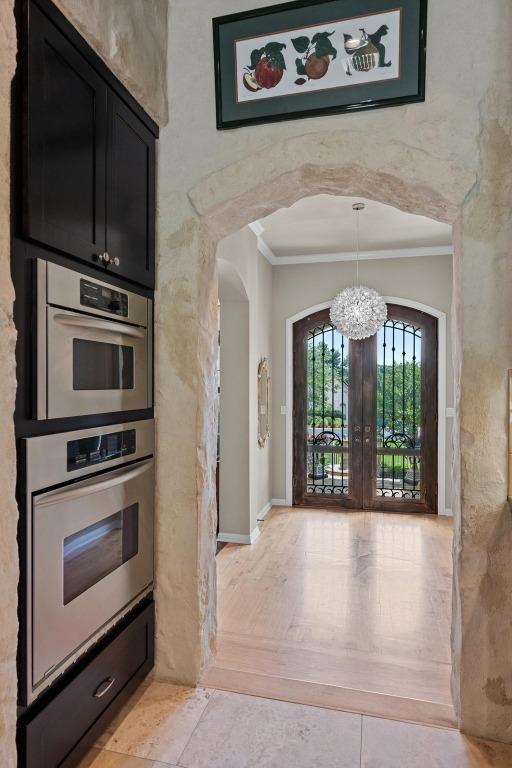 interior space with french doors, arched walkways, baseboards, an inviting chandelier, and ornamental molding