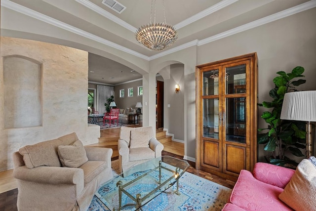 living room with visible vents, crown molding, wood finished floors, a chandelier, and arched walkways