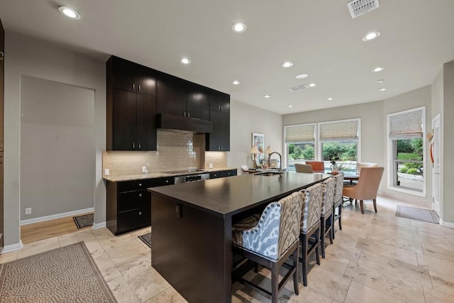 kitchen with decorative backsplash, visible vents, a sink, baseboards, and dark cabinetry