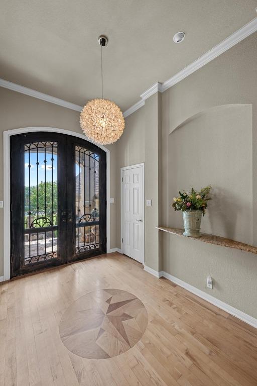 entrance foyer featuring baseboards, ornamental molding, french doors, and wood finished floors