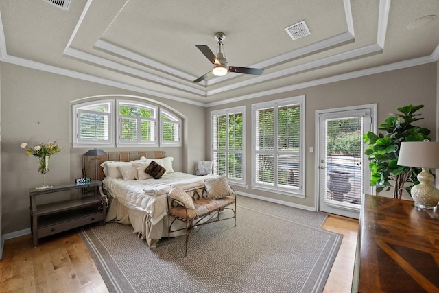 bedroom with multiple windows, a tray ceiling, access to outside, and visible vents