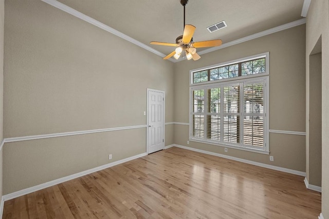 empty room featuring baseboards, ceiling fan, wood finished floors, and visible vents