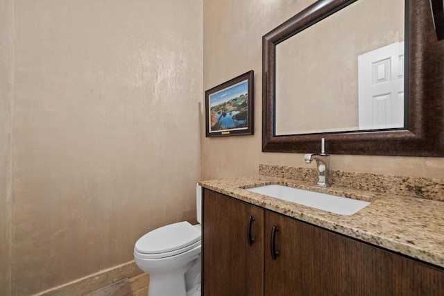 bathroom with toilet, baseboards, and vanity