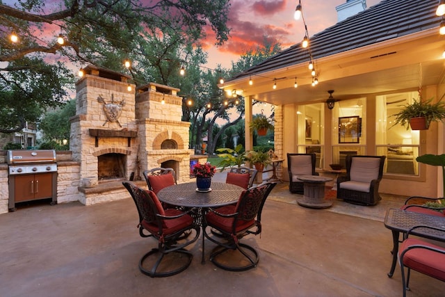 109 Lost Spur, Horseshoe Bay, TX 78657 - patio terrace at dusk featuring an outdoor stone fireplace, outdoor dining area, and grilling area