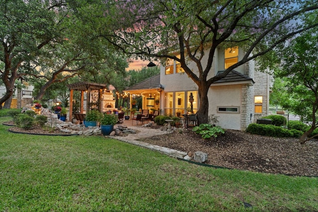 109 Lost Spur, Horseshoe Bay, TX 78657 - back of property featuring a patio, a lawn, stucco siding, and stone siding