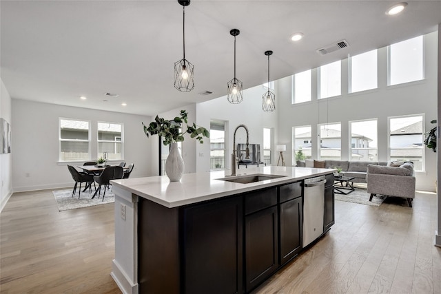 kitchen featuring stainless steel dishwasher, visible vents, open floor plan, a sink, and light wood-style flooring